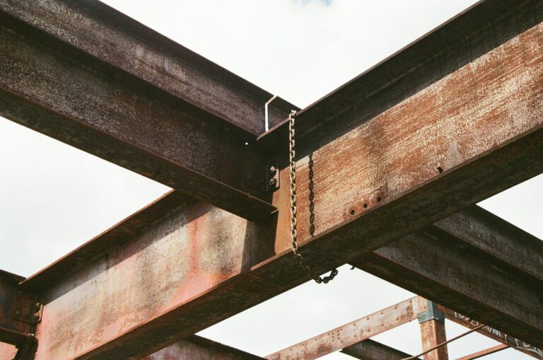 Close-up of rusty steel beams and chains in outdoor industrial construction site.