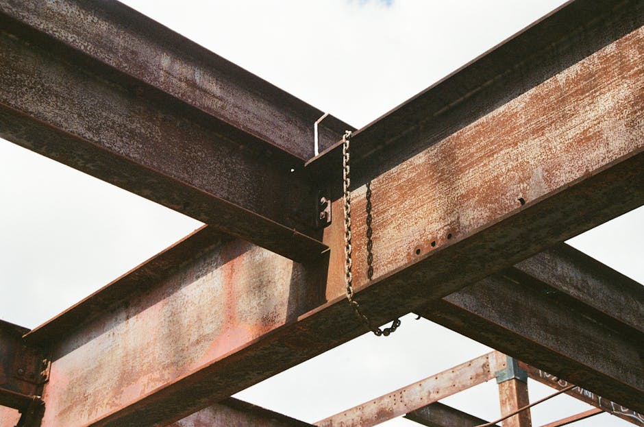 Close-up of rusty steel beams and chains in outdoor industrial construction site.